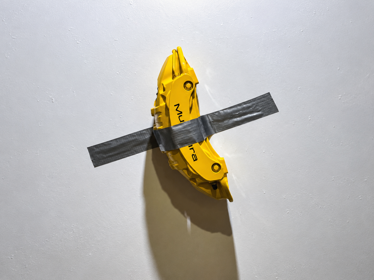 Banane jaune fixée au mur par du ruban adhésif gris